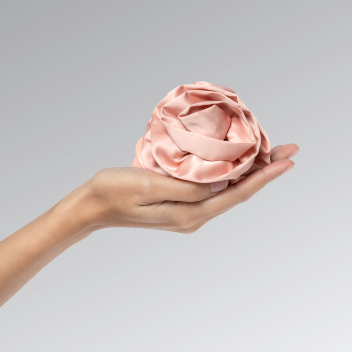 Hand holding a terracotta rosette flat clip against a gray background