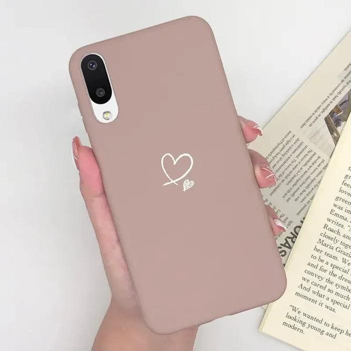 a woman holding a pink phone case with a heart on it