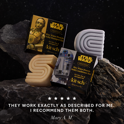 5-star customer review creative product shoot for KITSCH x Star Wars™ Solid Shampoo & Conditioner Combo on dark space-themed rocky background — C-3PO shampoo bar, R2-D2 conditioner bar, and both Star Wars gift boxes styled on rocks with galaxy backdrop — Mary M.: "THEY WORK EXACTLY AS DESCRIBED FOR ME. I RECOMMEND THEM BOTH."
