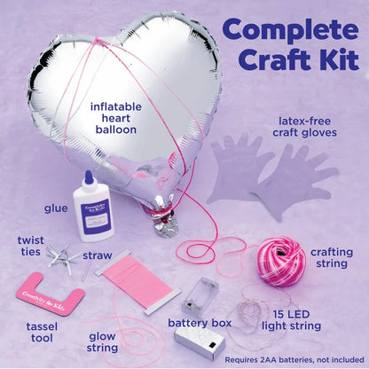 Complete craft kit with inflatable heart balloon, glue, and various crafting supplies on a purple background.