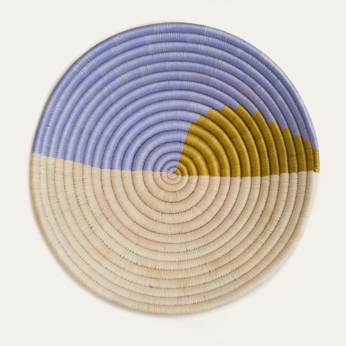 Round woven basket with blue, beige, and yellow color pattern on a white background