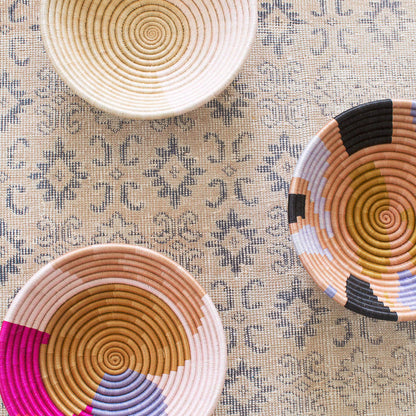 Three woven baskets with spiral patterns on a textured surface