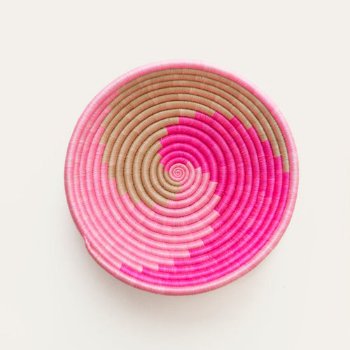 Pink and beige woven circular basket on a white background
