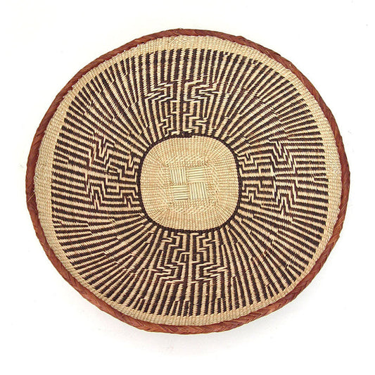 A round, beige-colored woven basket with a geometric pattern and a coiled rim.