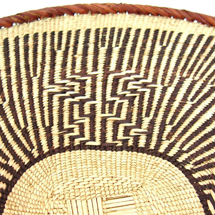 A round, beige-colored woven basket with a geometric pattern and a coiled rim.