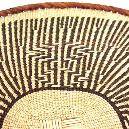 A round, beige-colored woven basket with a geometric pattern and a coiled rim.