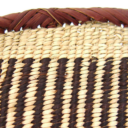 A round, beige-colored woven basket with a geometric pattern and a coiled rim.