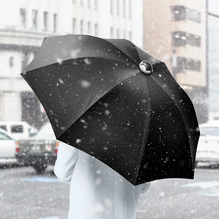 Person holding a black umbrella in a snowy city street