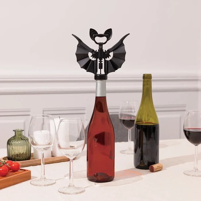 Bottle opener shaped like a bat on a wine bottle with glasses and another bottle in the background.