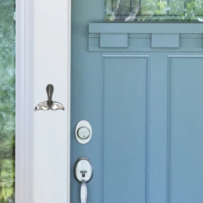 Silver whale tail-shaped object on a white doorframe with blue door