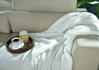 White knitted throw blanket, folded on sofa armrest with textured knit surface