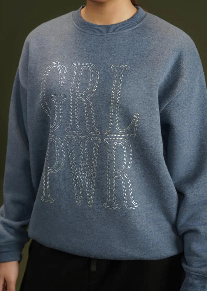 Blue knit sweatshirt close-up with glitter 'GRL' rhinestone-style chest lettering