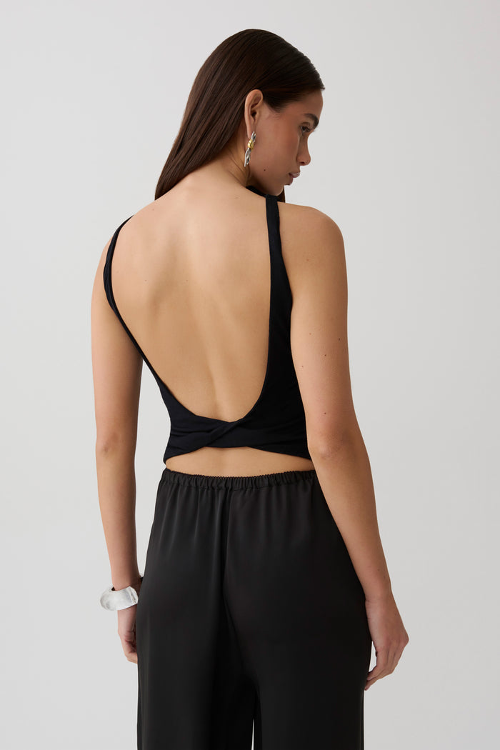Woman wearing black backless twist top.